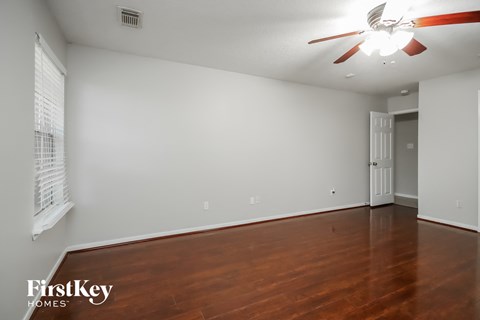 the living room and dining room with wood floors and a ceiling fan