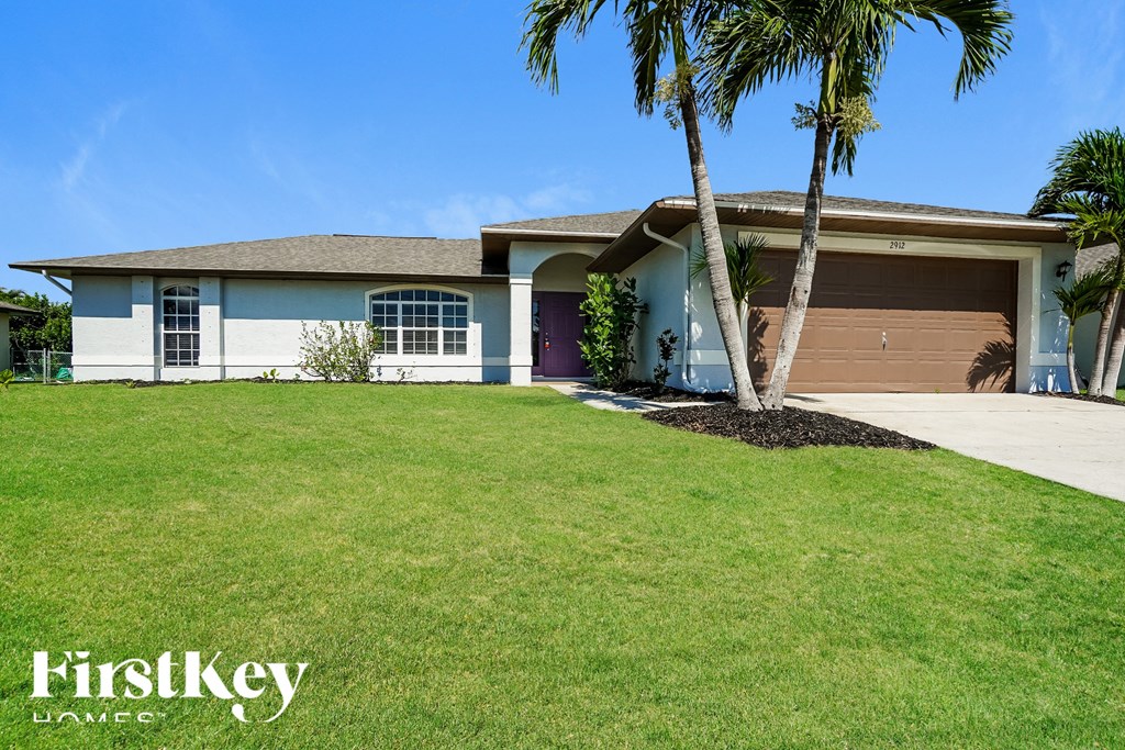 a house with a lawn and palm tree in front of it