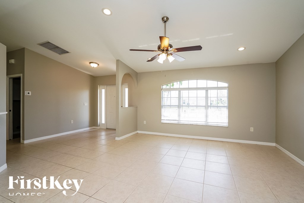 an empty living room with a ceiling fan