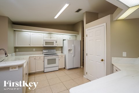 a kitchen with white cabinets and appliances and a white refrigerator