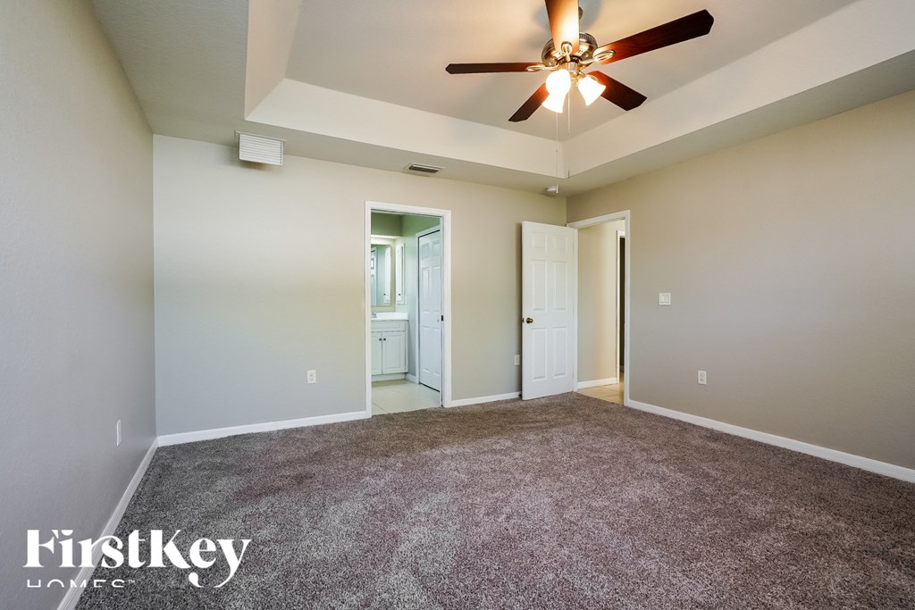 an empty living room with carpet and a ceiling fan