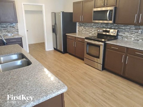 A kitchen with a granite counter top and wooden floors.