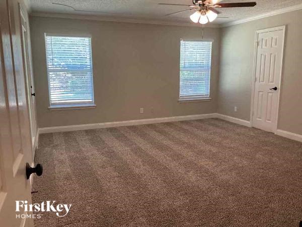 an empty room with a ceiling fan and two windows