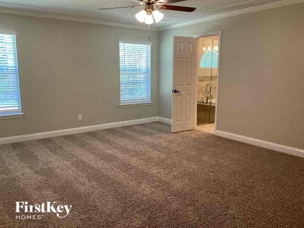 an empty room with a ceiling fan and a door to a bathroom