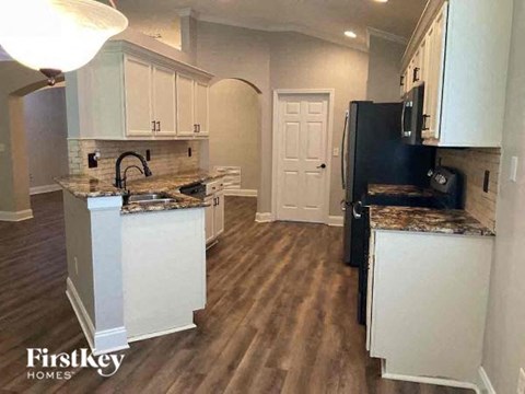 a kitchen with white cabinets and a black refrigerator