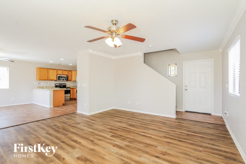 an empty living room with a ceiling fan and a kitchen