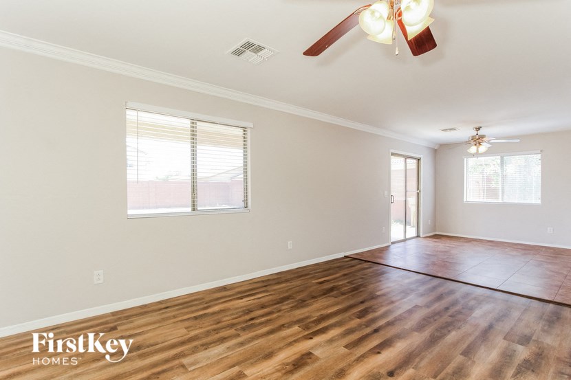 an empty living room with wood flooring and a ceiling fan