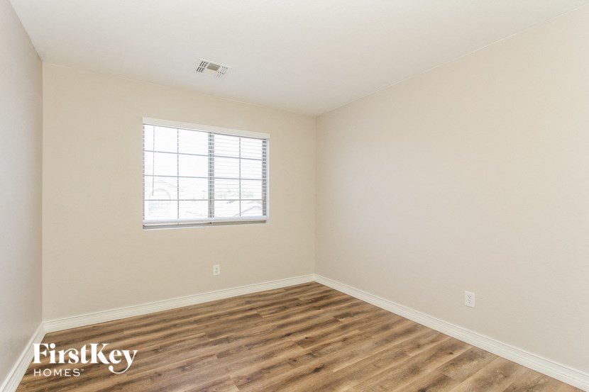 an empty room with a window and wood flooring