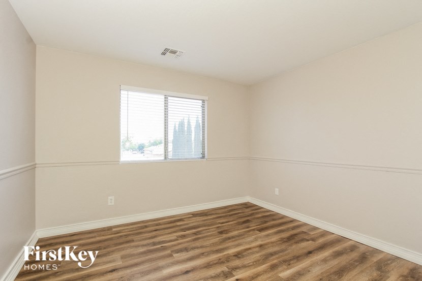 an empty bedroom with a window and wood flooring