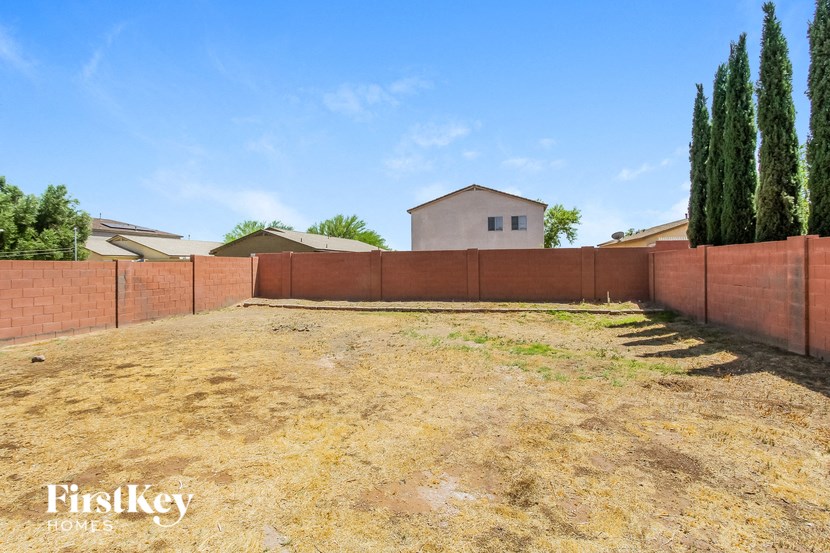 a backyard with a fence and a house in the background