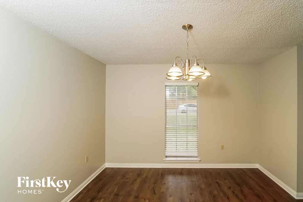 a bedroom with hardwood floors and a window and a chandelier