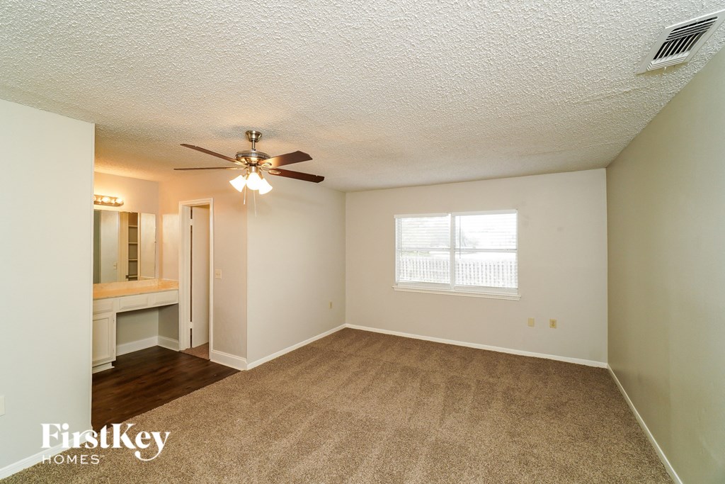 an empty living room with a ceiling fan and a window