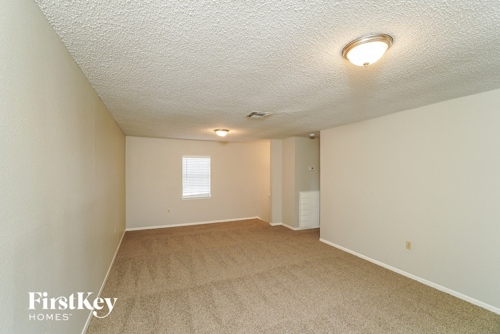 a spacious living room with beige carpet and white walls