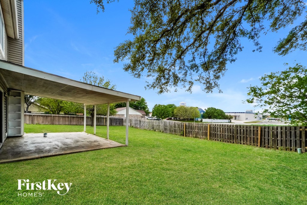 a backyard with a grass lawn and a wooden fence