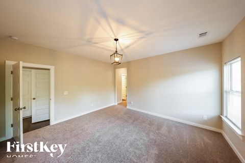 A spacious room with a carpeted floor and a hanging light fixture.
