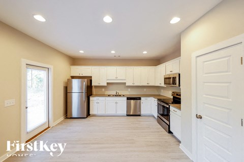A kitchen with white cabinets and a refrigerator.