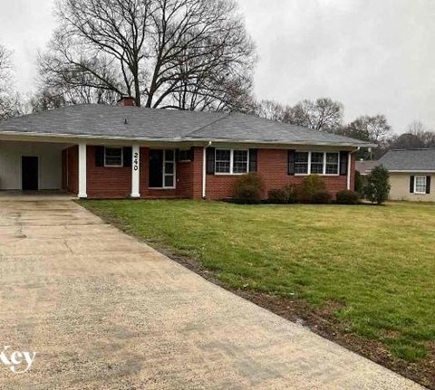 a brick house with a lawn and a driveway