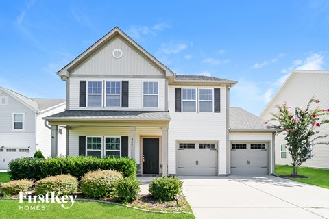 a white house with two garage doors and a lawn