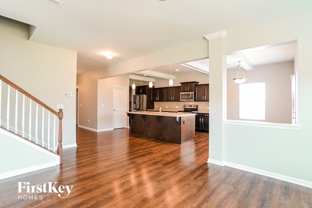 a renovated living room and kitchen with wood flooring and a staircase