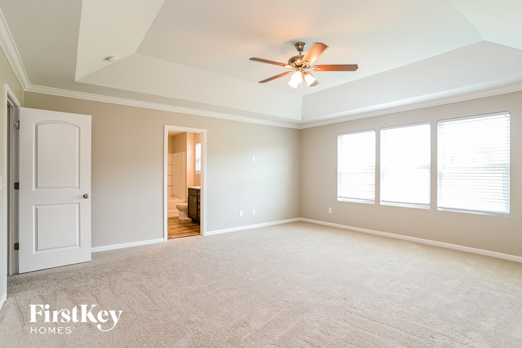 an empty living room with a ceiling fan and three windows