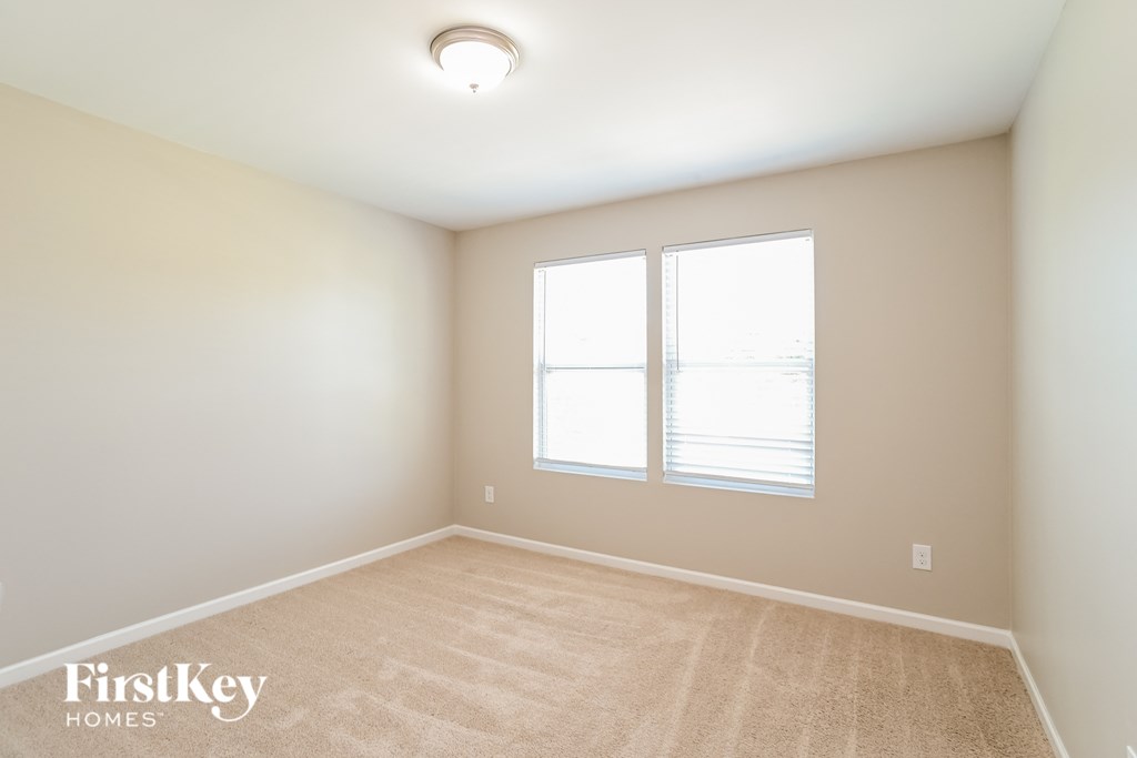 a spacious room with two windows and a carpeted floor
