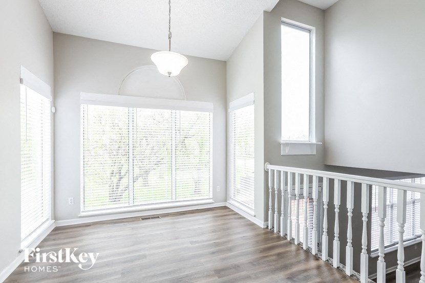 an empty living room with a staircase and a large window
