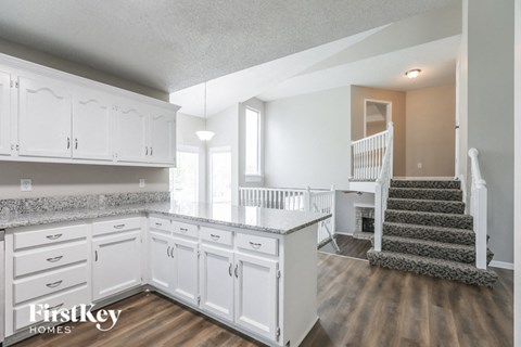 a white kitchen with white cabinets and a staircase