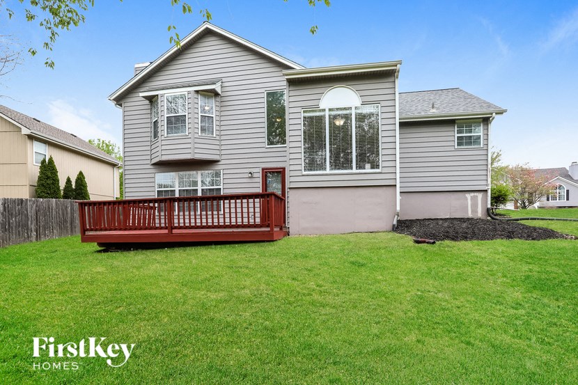 a house with a deck in front of a yard