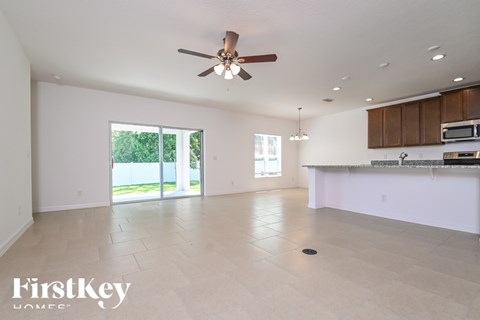 A spacious, empty room with a ceiling fan and sliding glass doors leading to a backyard.