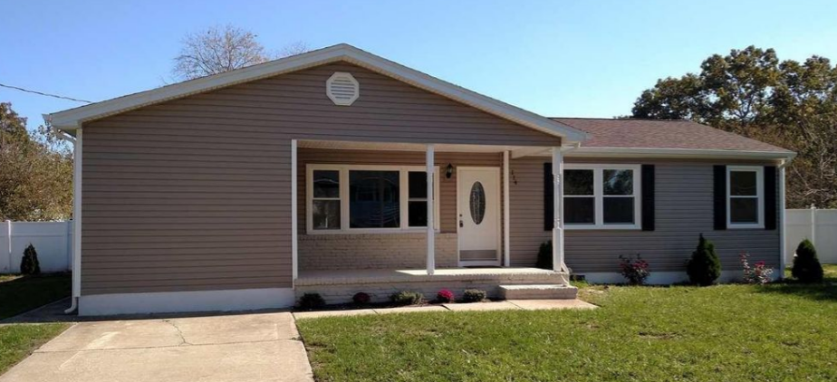 a brown house with a front porch and a lawn