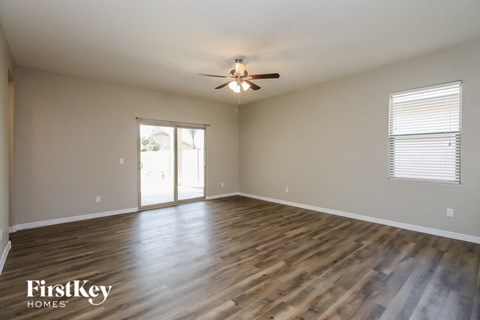 A spacious room with wooden flooring and a ceiling fan.