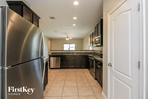 A kitchen with a stainless steel refrigerator and black cabinets.