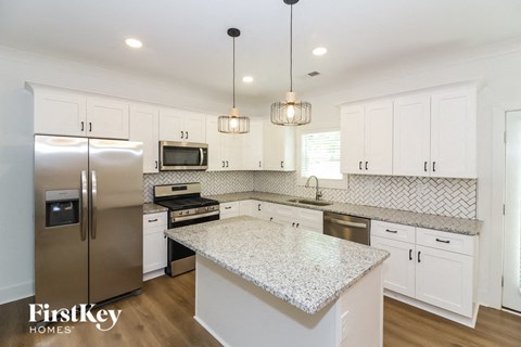 a white kitchen with a marble counter top and stainless steel appliances