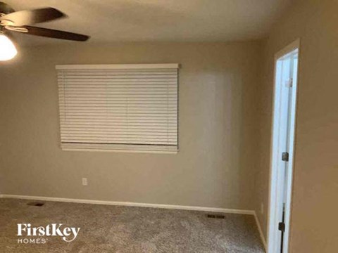 an empty room with a window and a ceiling fan