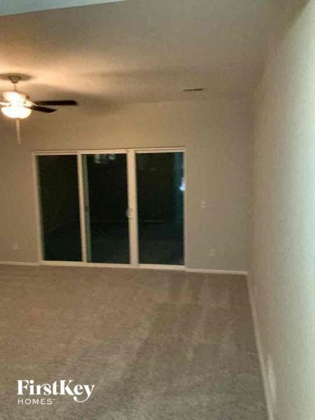 an empty living room with a ceiling fan and a window