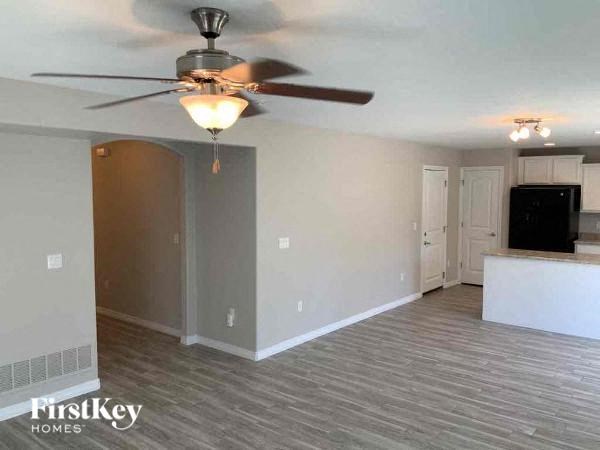 an empty living room with a ceiling fan