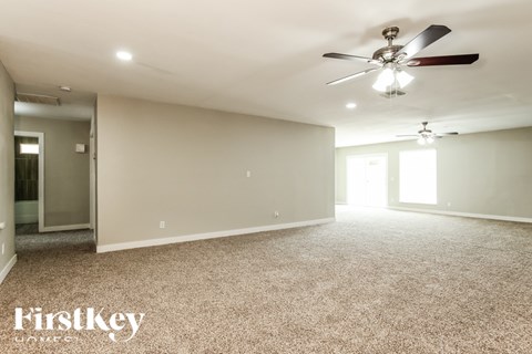 A spacious room with a ceiling fan and carpeted floor.
