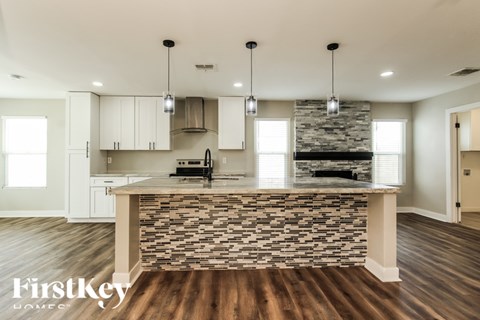 A kitchen with a stone counter and wooden floors.