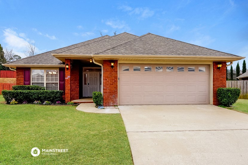 a small brick house with a driveway and a garage door