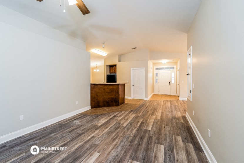 the living room and kitchen of a manufactured home with wood flooring