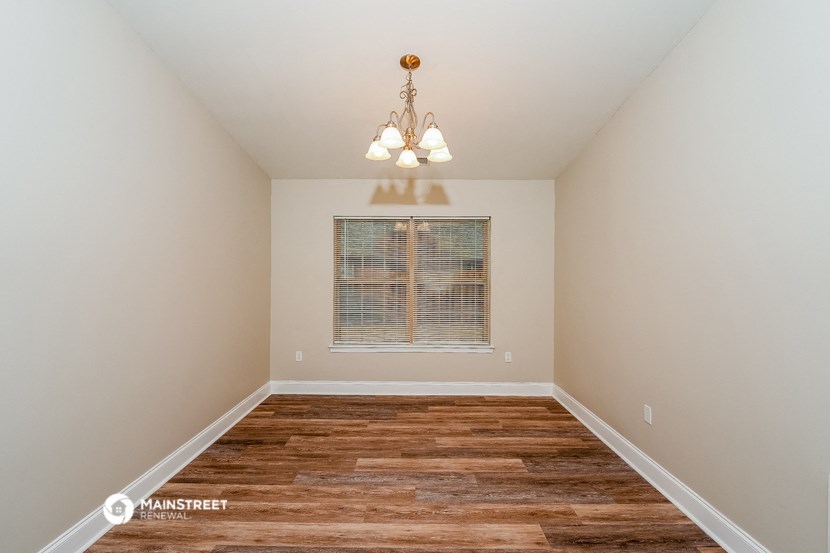 the spacious living room with wood floors and a chandelier