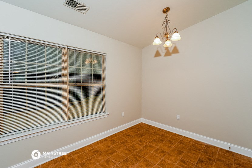 the living room of a home with a large window and wood flooring