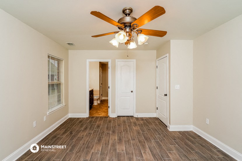 a living room with a ceiling fan and a door to a hallway