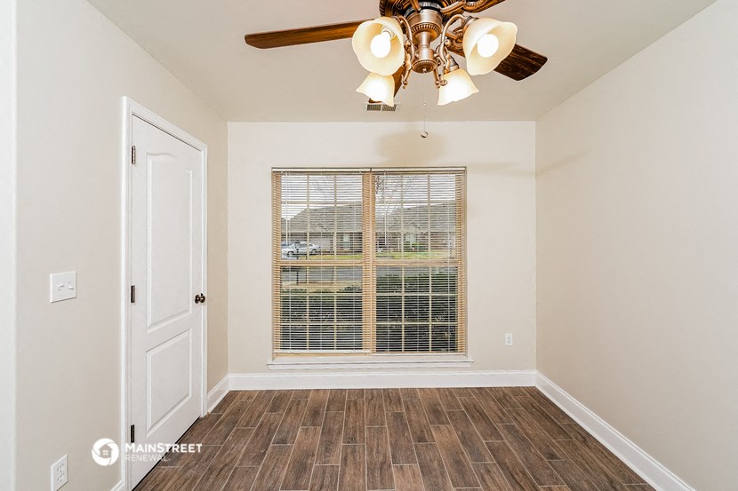 the living room of a home with a large window and a ceiling fan