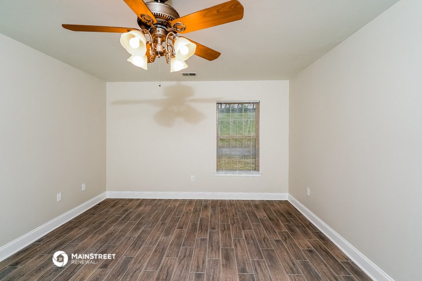 the living room of a home with a ceiling fan and wood floors