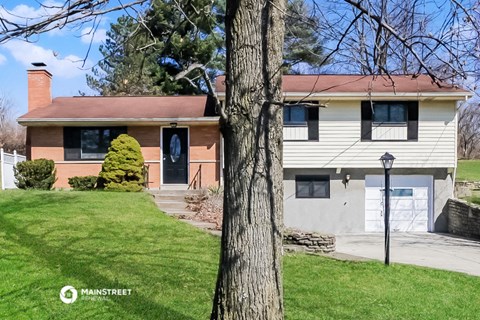 a white house with a red roof and a tree