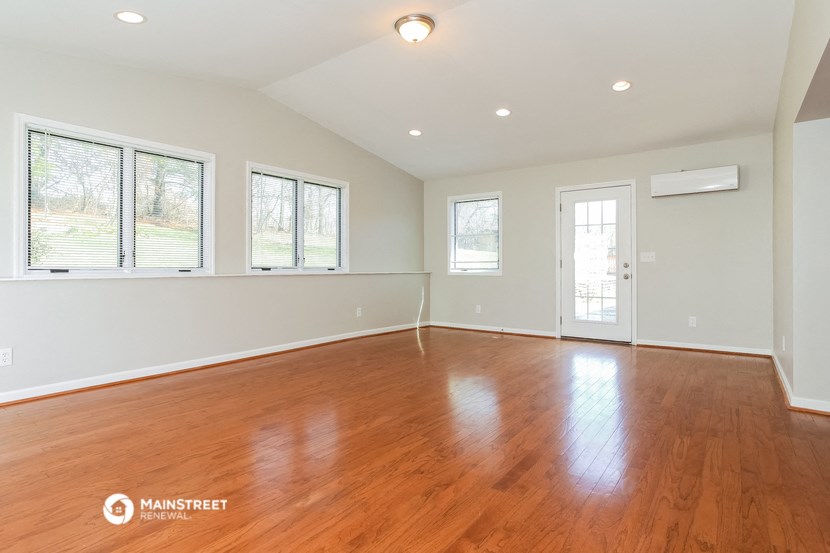 an empty living room with wood floors and white walls