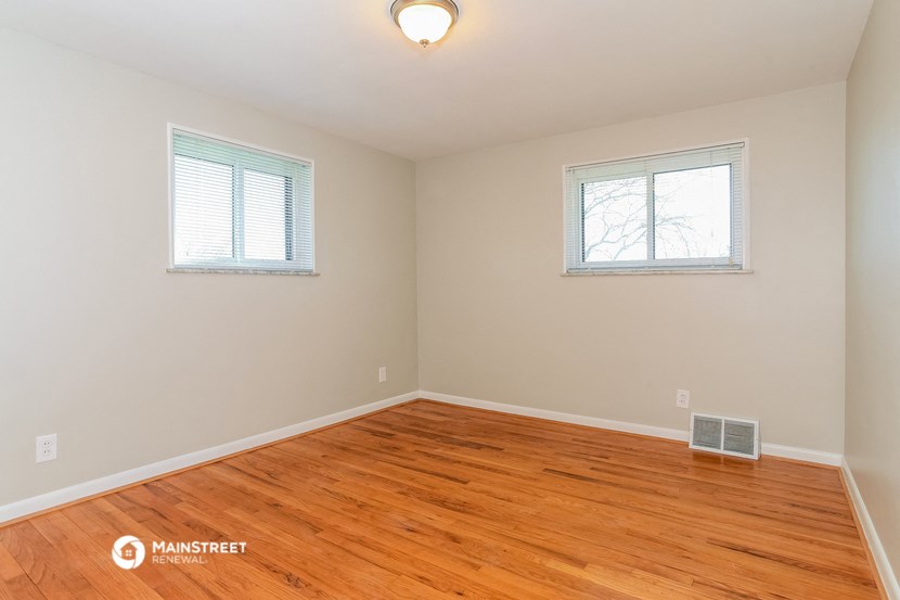 the living room with hardwood floors and two windows