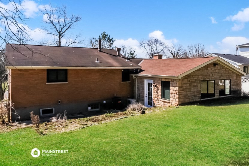 a brick house with a brown roof and a green lawn