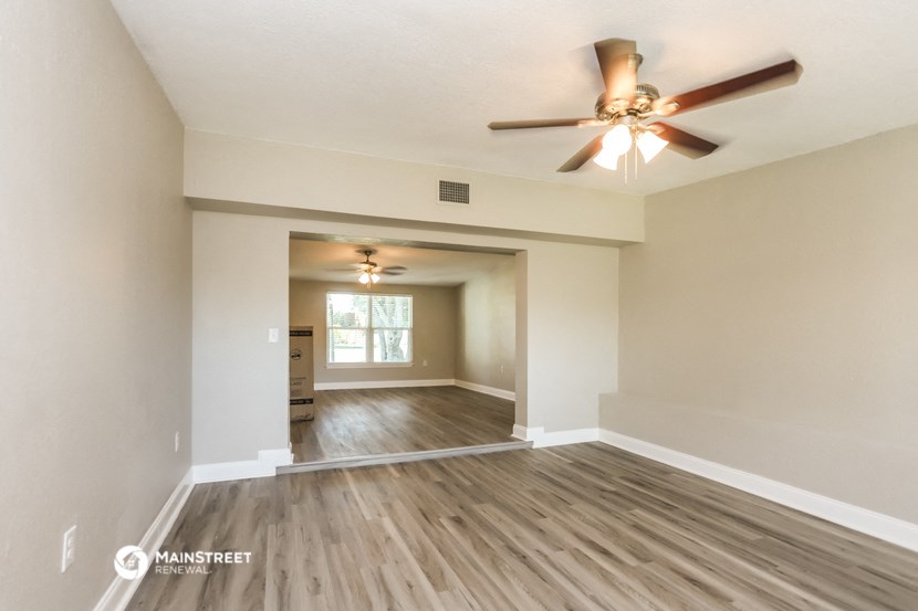 the spacious living room with ceiling fan and hardwood flooring